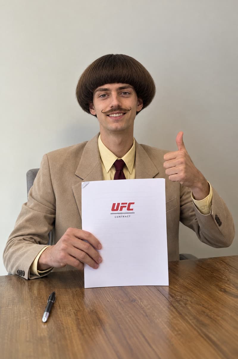 Archibald Brown holding up his UFC contract with a thumbs up